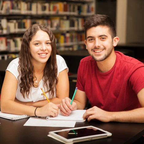 Two young professionals collaborating during a corporate training session and taking notes